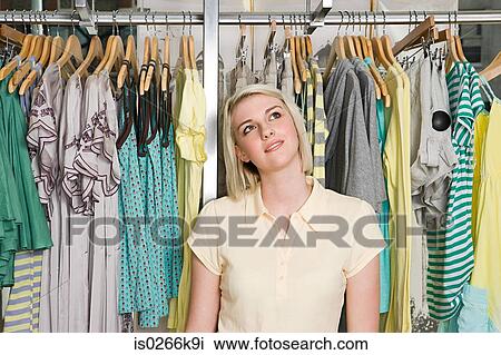 Stock Image - Woman daydreaming in a clothes store. Fotosearch