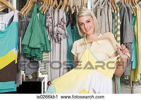 Woman holding a dress in a clothes store View Large Photo Image Stock Image - Woman holding a dress in a clothes store. Fotosearch