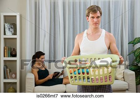 A man doing laundry whilst a woman relaxes View Large Photo Image Stock Photo - A man doing laundry whilst a woman relaxes. Fotosearch