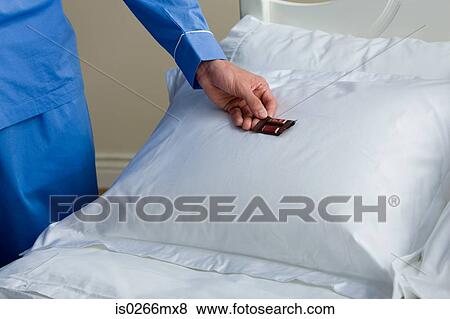 A man putting a chocolate on a pillow View Large Photo Image Stock Photo - A man putting a chocolate on a pillow. Fotosearch