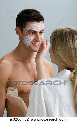 A woman applying face mask to a mans face View Large Photo Image Stock Image - A woman applying face mask to a mans face. Fotosearch