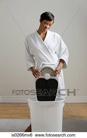 Young woman putting bathroom scales in the bin View Large Photo Image Stock Photograph - Young woman putting bathroom scales in the bin. Fotosearch
