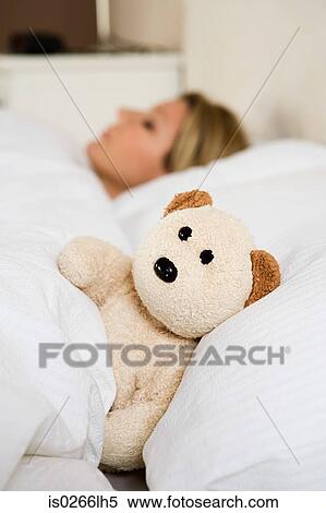 Stock Photography - Woman in bed with teddy bear. Fotosearch