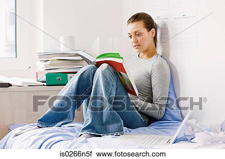 Stock Image - Student reading in room. Fotosearch