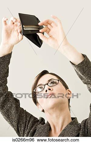 A young woman looking in an empty wallet View Large Photo Image Stock Photograph - A young woman looking in an empty wallet. Fotosearch