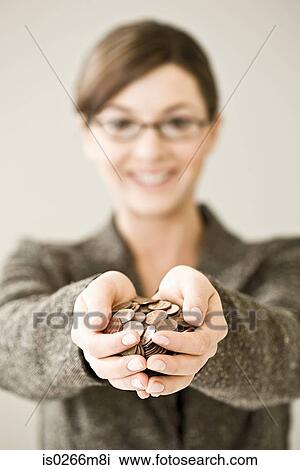 Stock Image - Young woman holding a pile of coins. Fotosearch