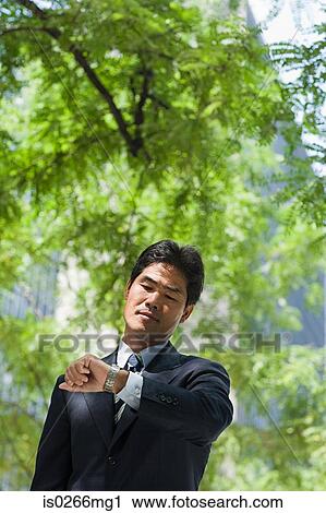 Businessman looking at his watch View Large Photo Image Stock Image - Businessman looking at his watch. Fotosearch