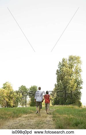 Couple walking in field View Large Photo Image Stock Image - Couple walking in field. Fotosearch