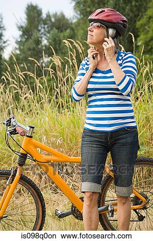 Woman putting on bicycle helmet View Large Photo Image Picture - Woman putting on bicycle helmet. Fotosearch