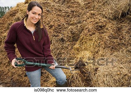 Stock Image - Woman moving a mound of straw. Fotosearch