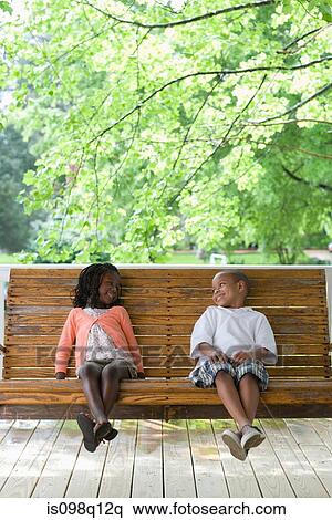 A boy and girl sitting on a swing seat View Large Photo Image Stock Photography - A boy and girl sitting on a swing seat. Fotosearch