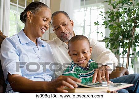 Stock Photograph - Grandparents and their grandson looking at a photo album. Fotosearch