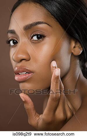Young woman applying foundation View Large Photo Image Stock Photo - Young woman applying foundation. Fotosearch