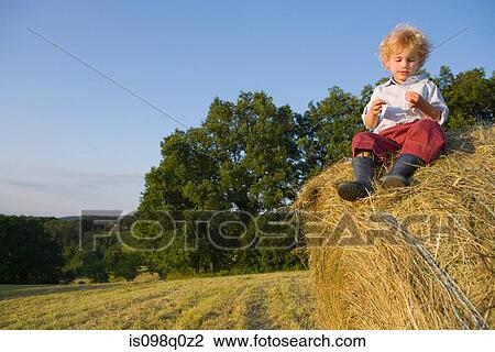 A boy sitting on a haystack View Large Photo Image Stock Image - A boy sitting on a haystack. Fotosearch