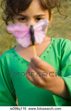A girl holding a toy butterfly View Large Photo Image Stock Photograph - A girl holding a toy butterfly. Fotosearch