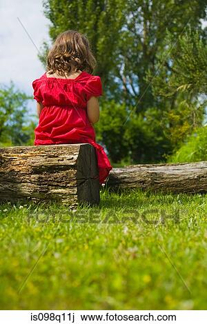 A girl sitting on a log View Large Photo Image Stock Image - A girl sitting on a log. Fotosearch