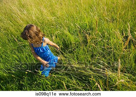 A girl walking through a field of long grass View Large Photo Image Stock Image - A girl walking through a field of long grass. Fotosearch