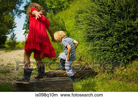 Boy and girl stepping on logs View Large Photo Image Picture - Boy and girl stepping on logs . Fotosearch