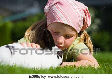 A girl stroking a rabbit View Large Photo Image Stock Photo - A girl stroking a rabbit. Fotosearch