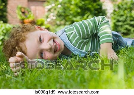 Portrait of a boy lying on grass View Large Photo Image Stock Photo - Portrait of a boy lying on grass. Fotosearch