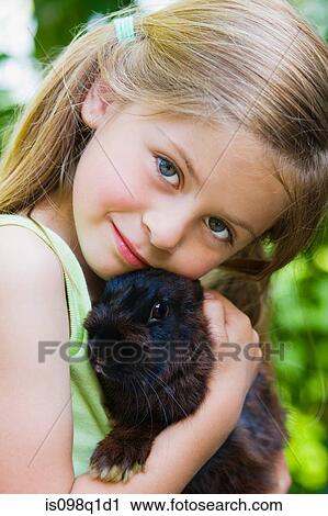 Portrait of a girl holding a rabbit View Large Photo Image Stock Image - Portrait of a girl holding a rabbit. Fotosearch
