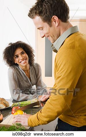 Stock Photography - A couple preparing food in a kitchen. Fotosearch