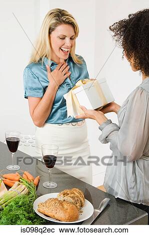 Stock Image - A woman giving a friend a present. Fotosearch
