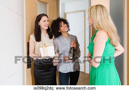 Stock Photography - A woman greeting friends at the door. Fotosearch