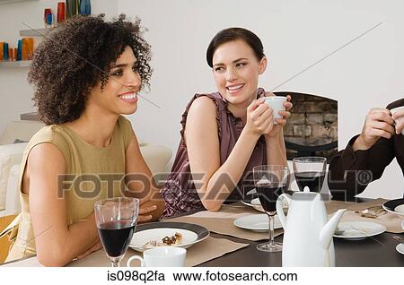 Stock Image - Friends having coffee and dessert at a dinner party. Fotosearch