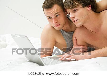 Stock Image - A gay couple using a laptop. Fotosearch