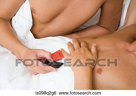 Stock Photograph - A man handing condoms to his partner. Fotosearch