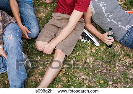 Men sitting on grass in a park View Large Photo Image Stock Image - Men sitting on grass in a park. Fotosearch