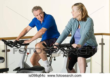 A man and woman using exercise bikes View Large Photo Image Stock Image - A man and woman using exercise bikes. Fotosearch