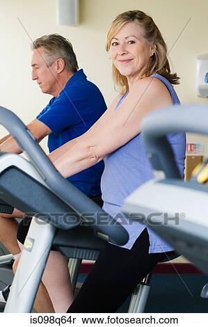 A man and woman using exercise bikes View Large Photo Image Stock Photography - A man and woman using exercise bikes. Fotosearch