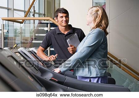 Stock Photo - A personal trainer and woman on a treadmill. Fotosearch