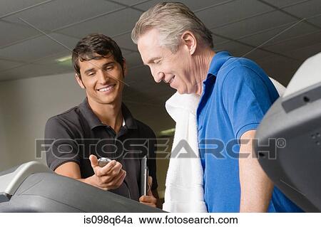 A personal trainer helping a man on a treadmill View Large Photo Image Stock Image - A personal trainer helping a man on a treadmill. Fotosearch