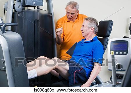 A personal trainer helping a man weightlift View Large Photo Image Picture - A personal trainer helping a man weightlift. Fotosearch