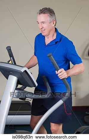 Mature man exercising on a cross trainer View Large Photo Image Picture - Mature man exercising on a cross trainer. Fotosearch