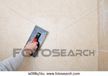 Stock Photograph - A decorator grouting tiles. Fotosearch
