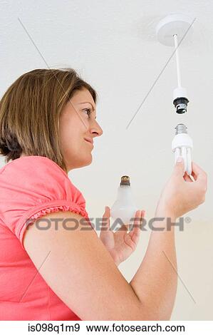 A young woman changing her lightbulb View Large Photo Image Stock Photo - A young woman changing her lightbulb. Fotosearch