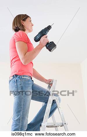 A young woman holding an electric drill View Large Photo Image Stock Image - A young woman holding an electric drill. Fotosearch