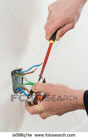 Stock Photo - An electrician fixing a socket. Fotosearch