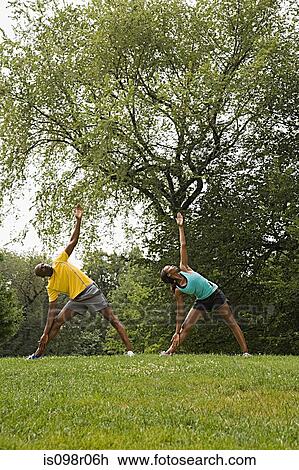 Stock Image - People doing yoga in park. Fotosearch