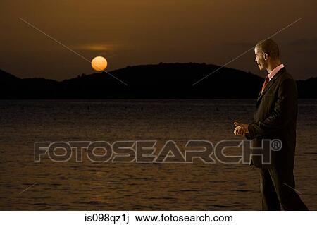 Businessman looking at sunset over sea View Large Photo Image Stock Image - Businessman looking at sunset over sea. Fotosearch