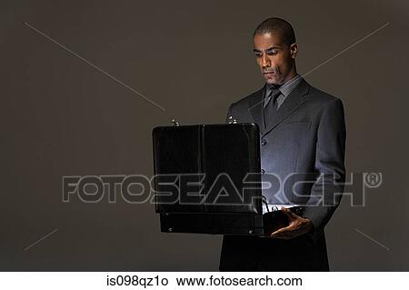 Businessman looking in briefcase View Large Photo Image Picture - Businessman looking in briefcase. Fotosearch