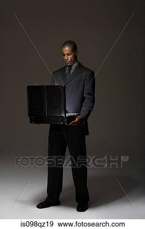 Businessman looking in briefcase View Large Photo Image Stock Photo - Businessman looking in briefcase. Fotosearch