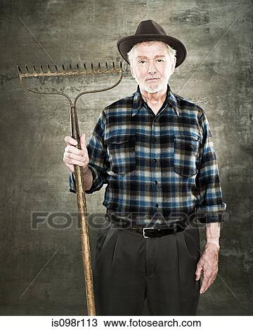 Portrait of a farmer holding a rake View Large Photo Image Stock Image - Portrait of a farmer holding a rake. Fotosearch