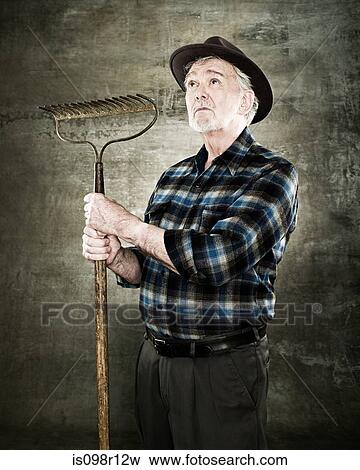 Portrait of a farmer holding a rake View Large Photo Image Stock Photo - Portrait of a farmer holding a rake. Fotosearch