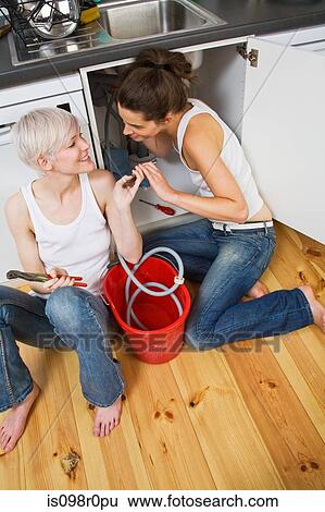Stock Photograph - A lesbian couple fixing a sink. Fotosearch