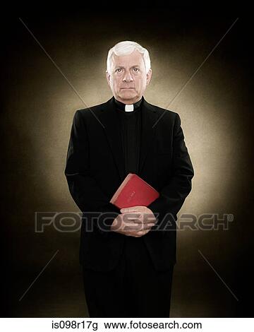 Stock Image - Portrait of a priest holding a bible. Fotosearch